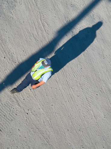 man walking in dirt parking lot from above