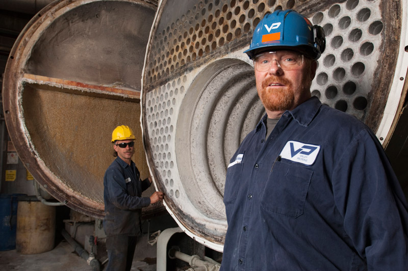 photograph of workers in an industrial setting with hardhats and safety glasses