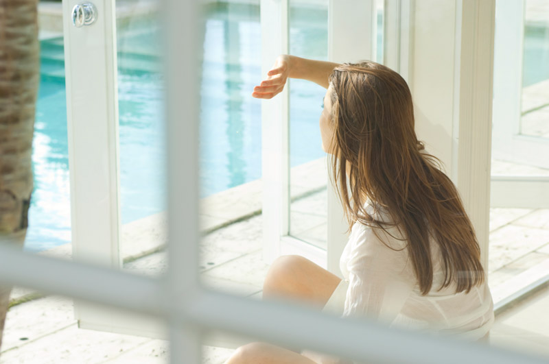 girl seated by pool shielding sun from eyes